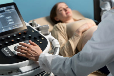 Ultrasound machine in use with a patient lying on an examination table.
