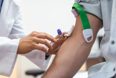 Person receiving a blood test with a green bandage on their arm.