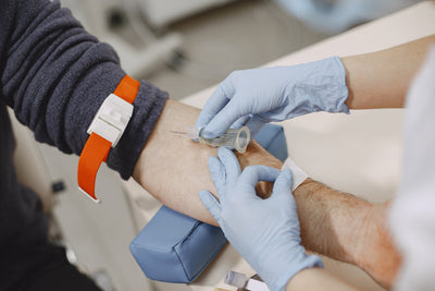 Person receiving a blood draw with gloves on hands