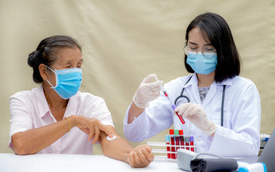 Doctor taking a blood sample from a patient wearing a face mask.