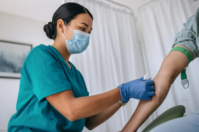 A close-up shot of a healthcare provider inserting a needle into a patient's arm to collect a blood sample for an anemia test.
