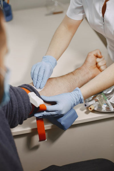 Person receiving a blood test with medical gloves on a white surface