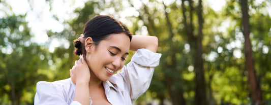 Woman adjusting her hair in a park with greenery in the background