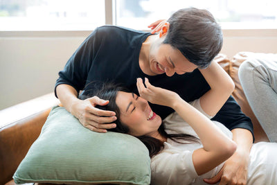 Couple embracing on a couch with a pillow, smiling and happy