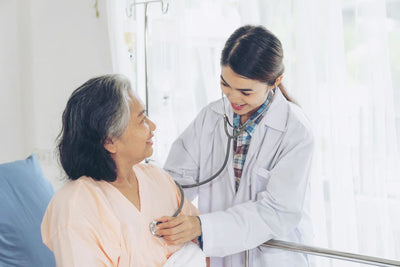 Doctor examining a patient in a hospital bed with a stethoscope.