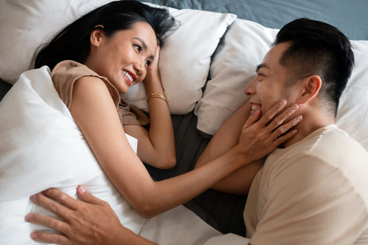 Couple lying in bed, smiling and embracing each other.