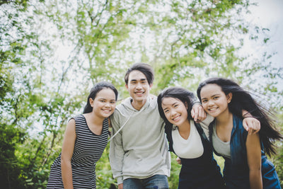 Four friends posing together in a park with white blossoms in the background