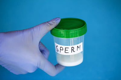 Hand holding a container containing semen sample for analysis of sperm quality