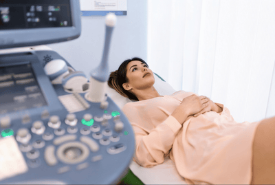 Woman lying on an ultrasound examination bed with medical equipment in a clinical setting