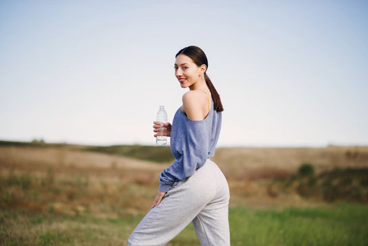 Woman holding a water bottle in a field after jogging