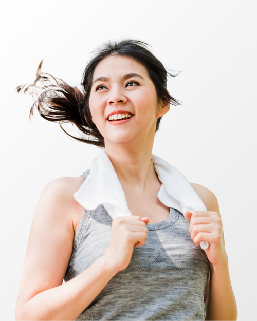 A smiling woman with dark hair blowing in the wind wears a white towel around her neck and a gray athletic tank top, set against a plain white background.