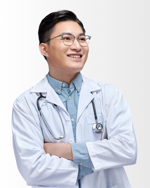 A smiling man wearing a white doctor's coat over a light blue button-up shirt, with a stethoscope around his neck and glasses, posed against a light gray studio background.